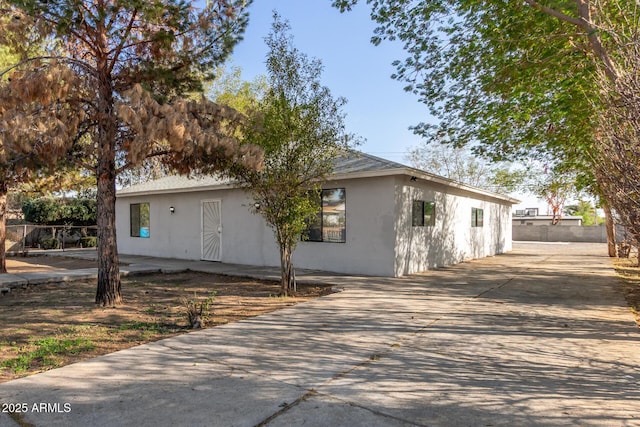 view of front of house featuring concrete driveway, fence, and stucco siding