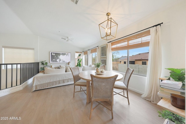 dining area featuring a chandelier, light hardwood / wood-style floors, and vaulted ceiling