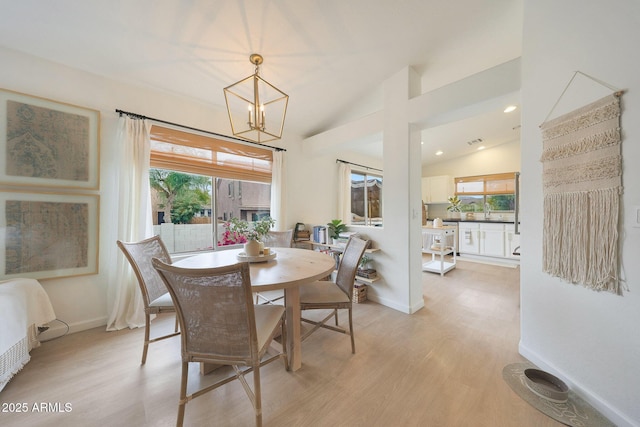 dining room featuring lofted ceiling, light hardwood / wood-style floors, and a notable chandelier