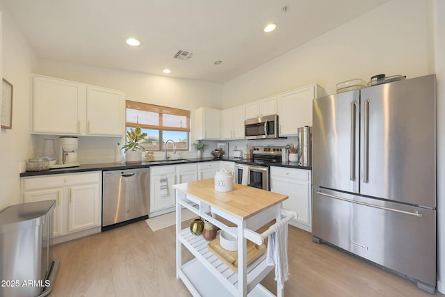 kitchen featuring white cabinetry, appliances with stainless steel finishes, sink, and light hardwood / wood-style flooring