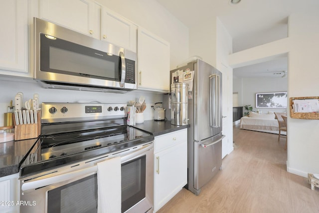 kitchen with light hardwood / wood-style floors, white cabinets, and appliances with stainless steel finishes