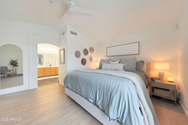 bedroom with lofted ceiling, connected bathroom, ceiling fan, and light wood-type flooring