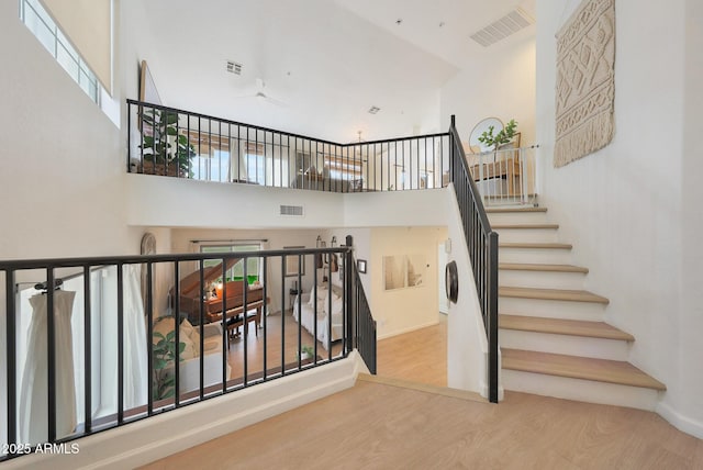 stairway with hardwood / wood-style flooring and a towering ceiling