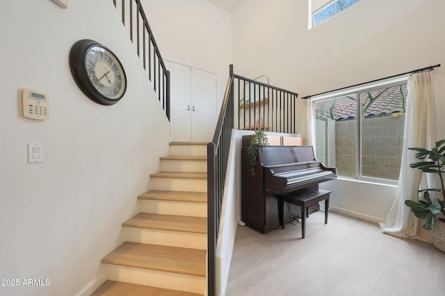 stairway with wood-type flooring and a high ceiling