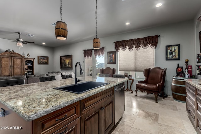 kitchen featuring light stone countertops, dishwasher, sink, hanging light fixtures, and an island with sink