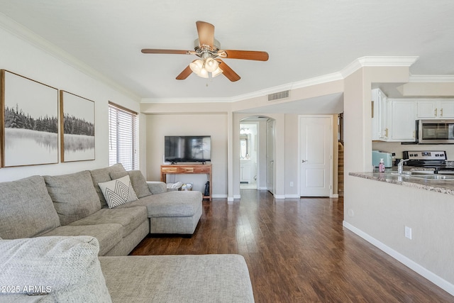 869 W Shellfish Dr, Gilbert, AZ 85233 - living area with arched walkways, crown molding, ceiling fan, dark wood-type flooring, and baseboards