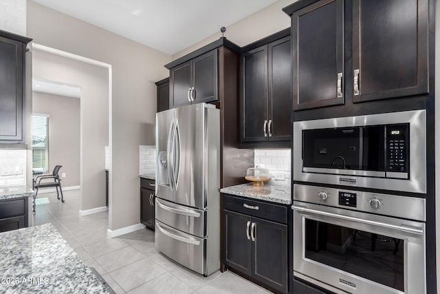 kitchen with tasteful backsplash, light stone countertops, appliances with stainless steel finishes, and light tile patterned floors