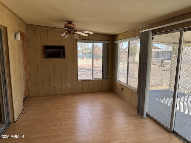 unfurnished sunroom featuring a wall mounted AC and a ceiling fan
