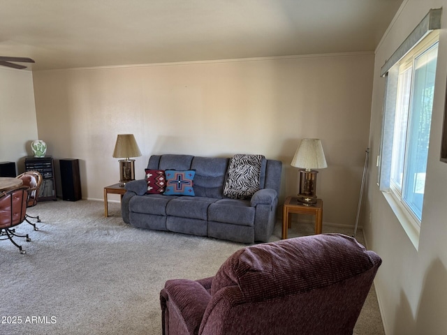 living room with a ceiling fan, crown molding, and light colored carpet