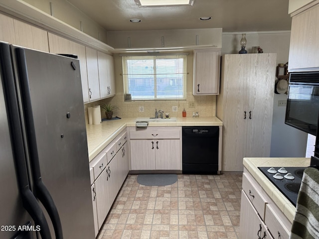 kitchen with a sink, light countertops, brick patterned floor, decorative backsplash, and black appliances