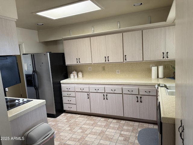 kitchen featuring light countertops, stainless steel refrigerator with ice dispenser, and decorative backsplash