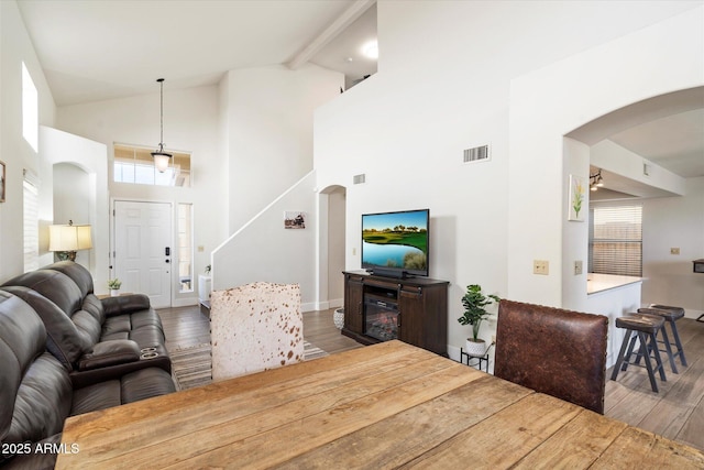 living room featuring wood-type flooring, beam ceiling, and high vaulted ceiling