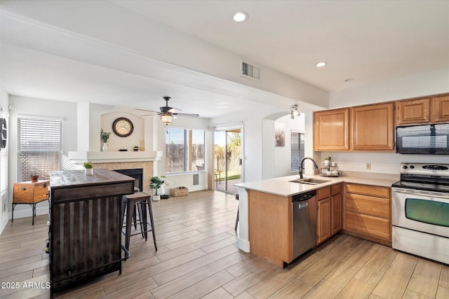 kitchen with a breakfast bar, sink, ceiling fan, kitchen peninsula, and stainless steel appliances