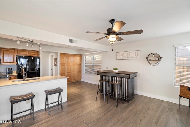 kitchen featuring sink, a breakfast bar area, black fridge with ice dispenser, and kitchen peninsula