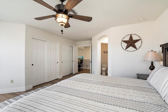 bedroom with multiple closets, ceiling fan, connected bathroom, and hardwood / wood-style floors