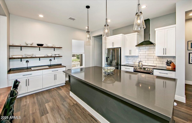 kitchen with white cabinets, backsplash, wall chimney range hood, and stainless steel appliances