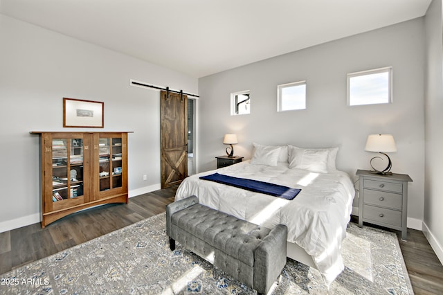 bedroom featuring a barn door and dark hardwood / wood-style floors