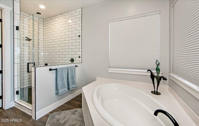 bathroom featuring shower with separate bathtub and wood-type flooring