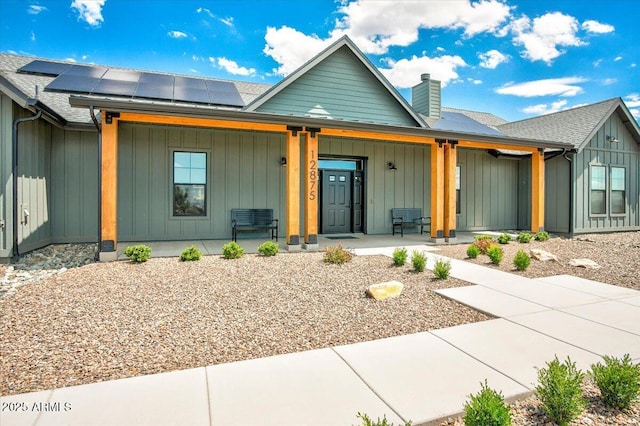 view of front of property featuring solar panels and a porch