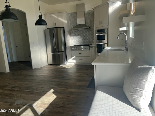 kitchen featuring appliances with stainless steel finishes, tasteful backsplash, sink, wall chimney range hood, and white cabinets