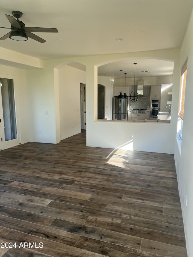 unfurnished living room with ceiling fan, sink, and dark wood-type flooring