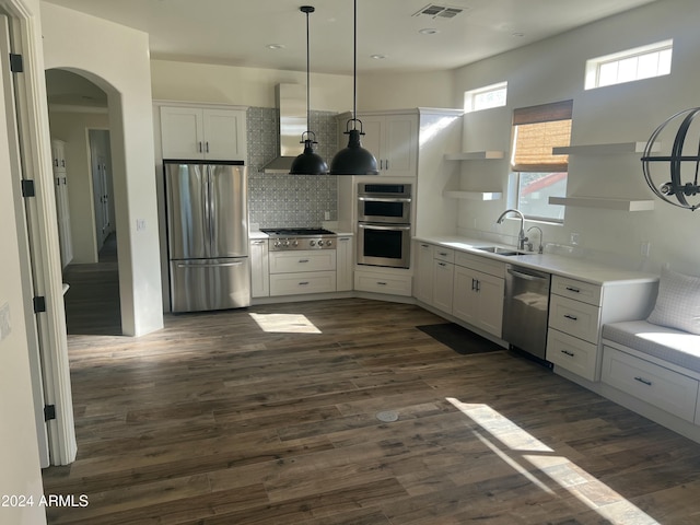 kitchen with sink, range hood, appliances with stainless steel finishes, decorative light fixtures, and white cabinetry