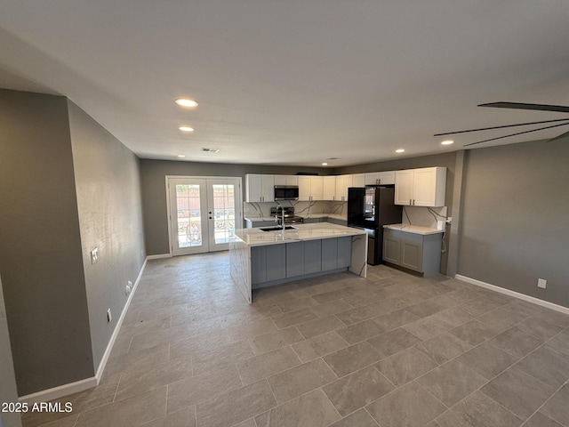 5042 S 22nd St, Phoenix, AZ 85040 - kitchen with stainless steel microwave, a sink, freestanding refrigerator, light countertops, and white cabinetry