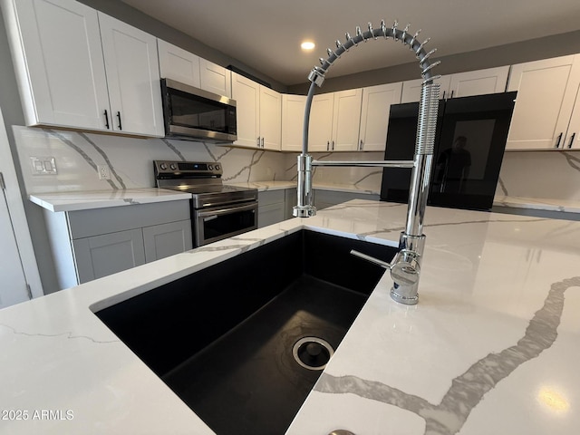 5042 S 22nd St, Phoenix, AZ 85040 - kitchen featuring stainless steel appliances, light stone counters, white cabinets, and backsplash