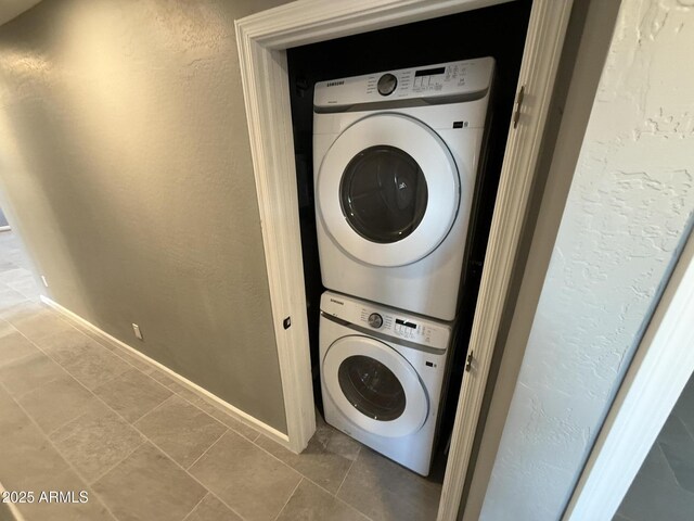 5042 S 22nd St, Phoenix, AZ 85040 - washroom featuring stacked washing machine and dryer, baseboards, a textured wall, and tile patterned floors