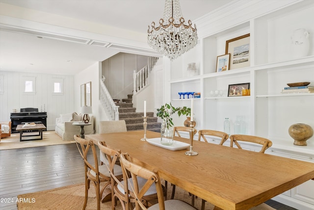 dining area with a chandelier, wood-type flooring, and wooden walls