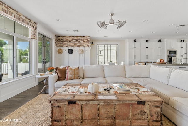 living room featuring sink, a healthy amount of sunlight, and dark hardwood / wood-style flooring