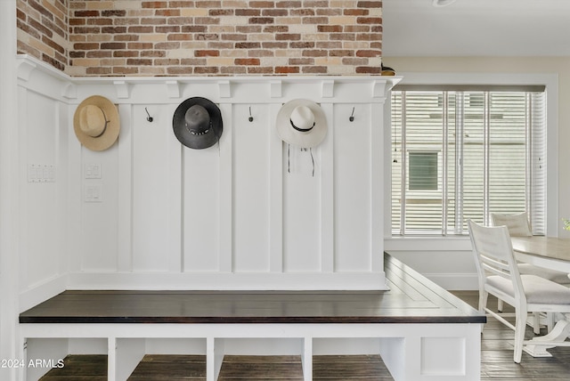 mudroom with brick wall and dark hardwood / wood-style floors