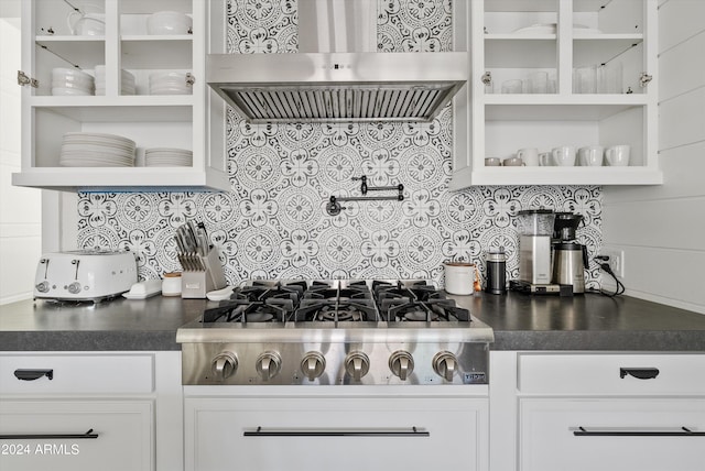 kitchen featuring wall chimney exhaust hood, stainless steel gas stovetop, white cabinets, and decorative backsplash