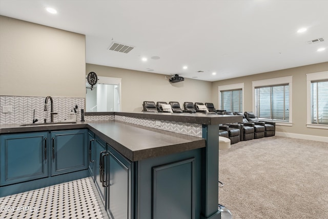 kitchen with kitchen peninsula, backsplash, sink, light colored carpet, and blue cabinetry