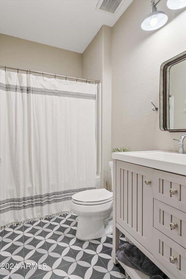 full bathroom with vanity, shower / bath combo with shower curtain, toilet, and tile patterned floors