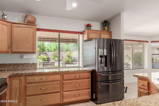 kitchen with light stone counters, stainless steel appliances, plenty of natural light, and light tile patterned floors