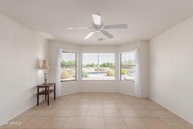 spare room featuring ceiling fan, light tile patterned flooring, and a wealth of natural light