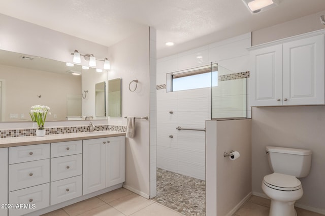 bathroom featuring tile patterned flooring, a textured ceiling, a shower, vanity, and toilet