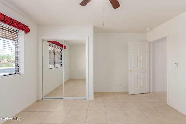 unfurnished bedroom with ceiling fan, a closet, light tile patterned floors, and multiple windows