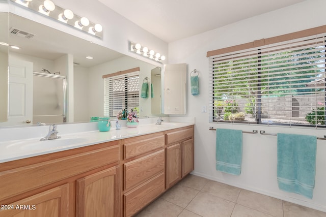 bathroom with tile patterned flooring, vanity, and a shower with door