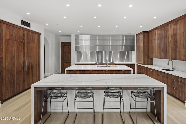 6852 E Fanfol Dr, Paradise Valley, AZ 85253 - kitchen with modern cabinets, light wood-style flooring, arched walkways, visible vents, and a spacious island