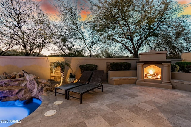 view of patio with a warm lit fireplace