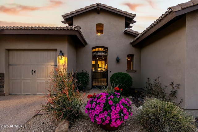 doorway to property featuring a garage and stucco siding