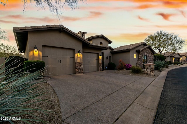 view of front of house with a garage, a tile roof, stone siding, driveway, and stucco siding