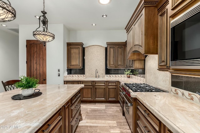 kitchen with black microwave, a sink, high end stainless steel range, decorative backsplash, and decorative light fixtures