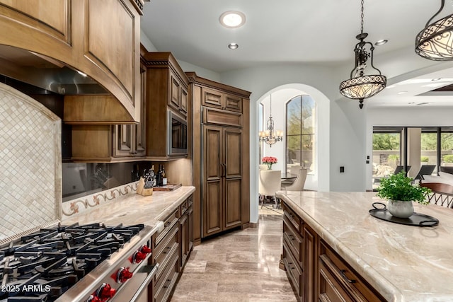 kitchen with stainless steel gas range oven, tasteful backsplash, arched walkways, decorative light fixtures, and recessed lighting