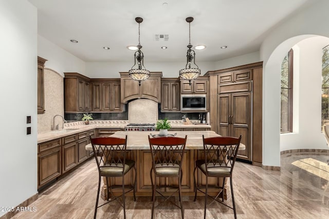 kitchen with a center island, custom exhaust hood, visible vents, a sink, and built in microwave