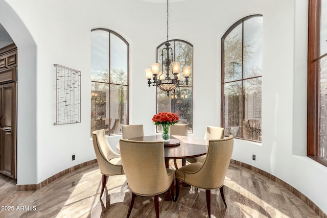 dining space with arched walkways, baseboards, and a notable chandelier