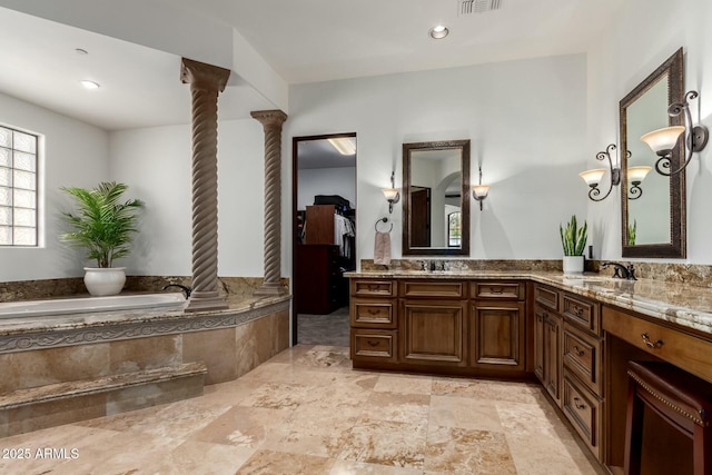 full bath with a garden tub, decorative columns, a sink, and double vanity