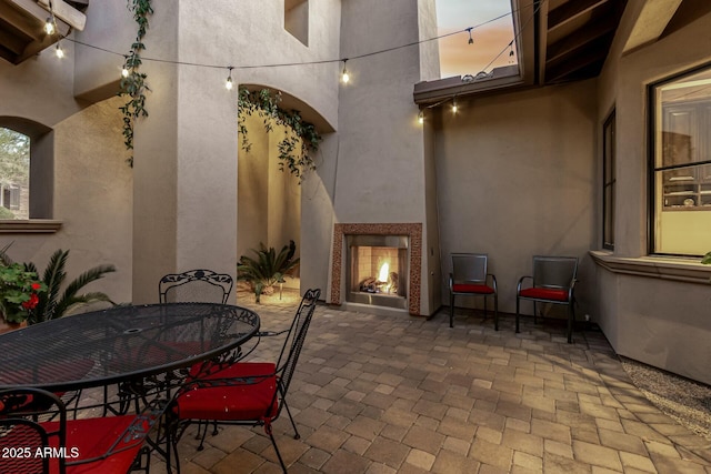 view of patio with a lit fireplace and outdoor dining area